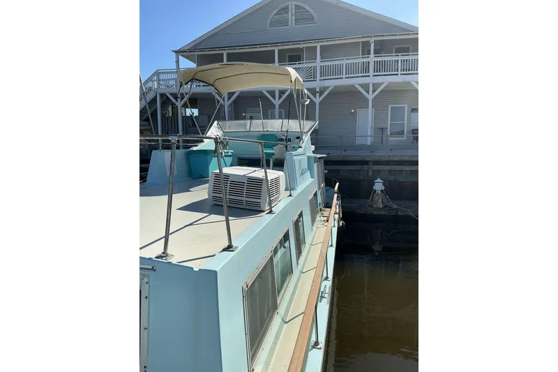 Slide: The Image of 1972 Whitcraft Hatteras boat docked near a wooden building under a clear blue sky. - 18