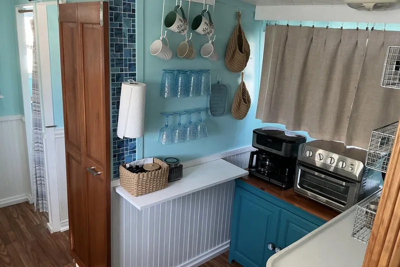 Slide: The Image of Cozy 1972 Whitcraft Hatteras kitchen with blue cabinets, appliances, and hanging mugs. - 28