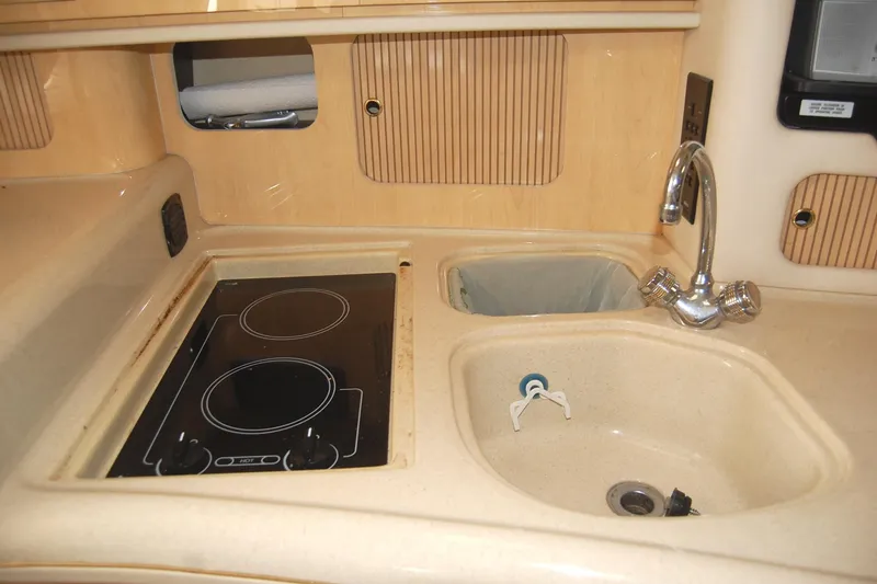 Slide: The Image of 2000 Sea Ray 340 Sundancer galley with stove, sink, and faucet in beige interior. - 18
