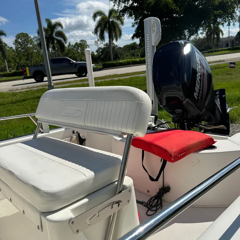Slide: The Image of 2014 Boston Whaler 150 Montauk boat with Mercury engine, parked near palm trees. - 13