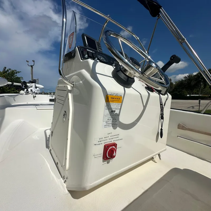 Slide: The Image of 2014 Boston Whaler 150 Montauk boat console with steering wheel under clear blue sky. - 15