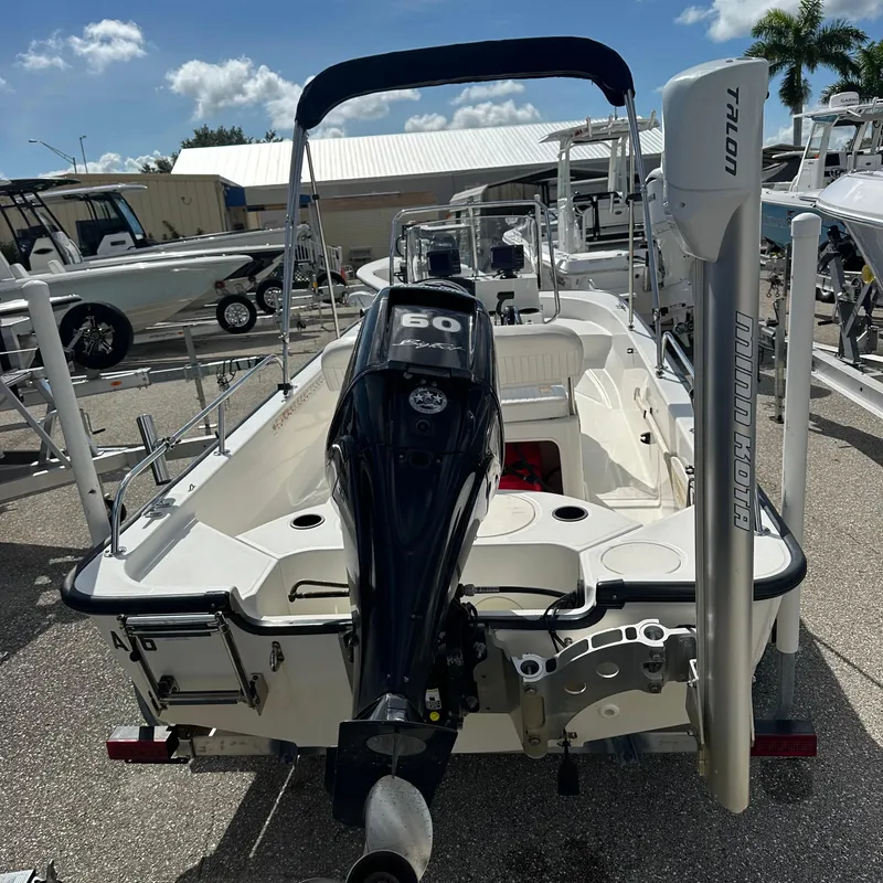 Slide: The Image of 2014 Boston Whaler 150 Montauk boat with outboard motor, docked under sunny skies. - 22