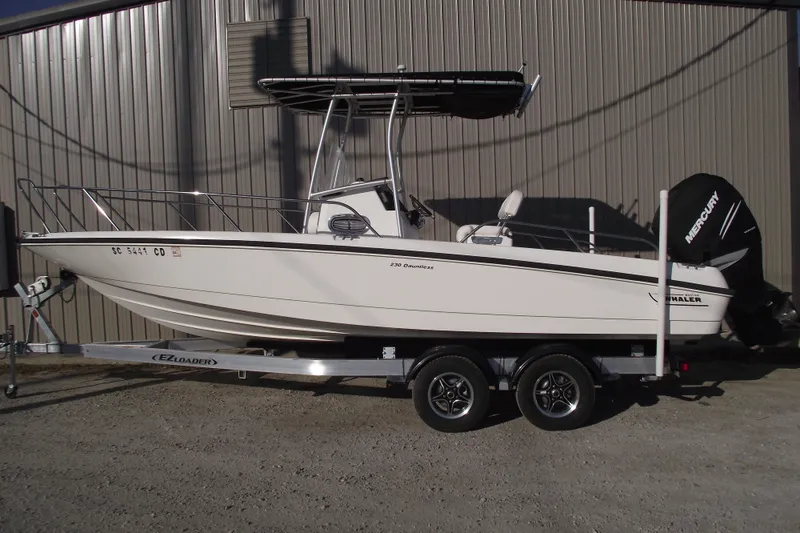 The Image of 2011 Boston Whaler 230 Dauntless boat on trailer, parked outdoors. - 0