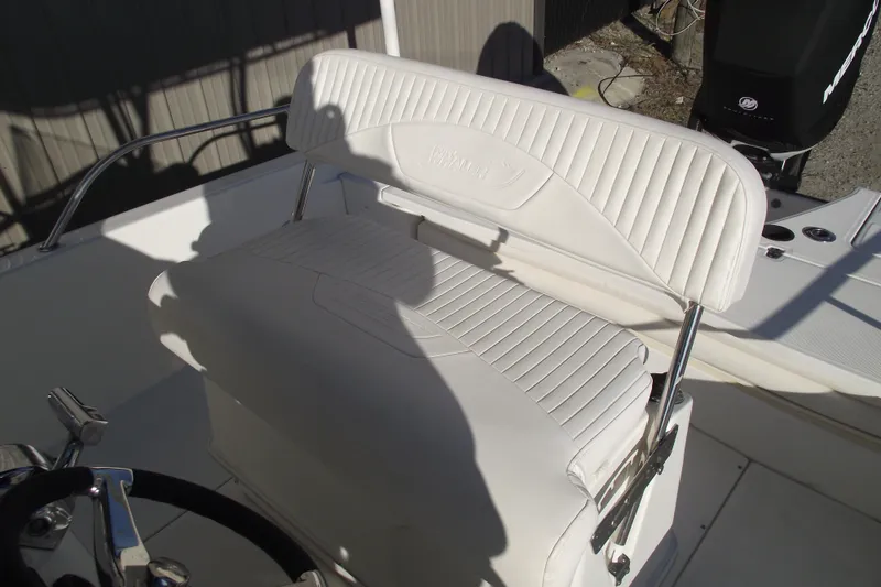 Slide: The Image of 2011 Boston Whaler 230 Dauntless boat seat with white upholstery and steering wheel. - 19