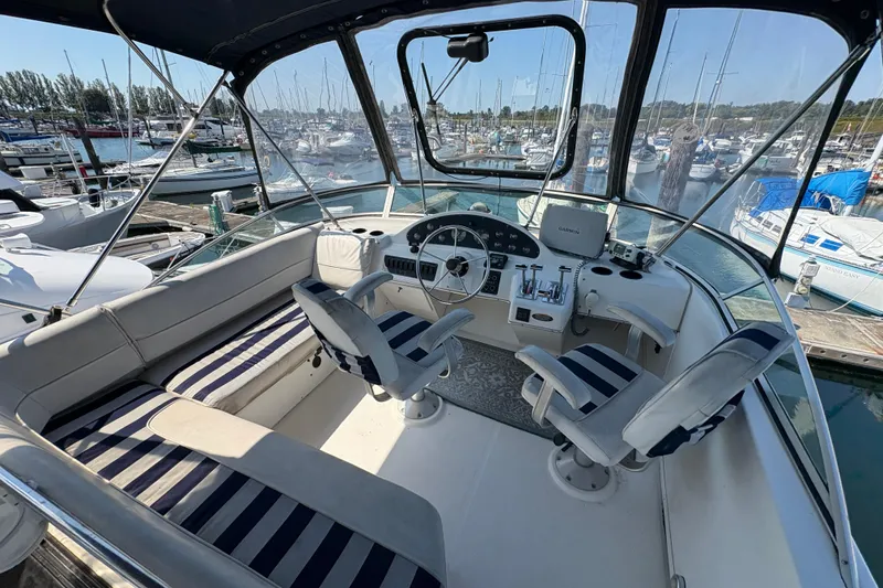 Slide: The Image of 1988 Bayliner 3587 Motoryacht cockpit with striped seating, marina view, and navigation equipment. - 28