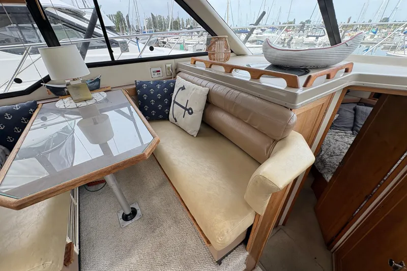 Slide: The Image of 1988 Bayliner 3587 Motoryacht interior with cozy seating, nautical decor, and marina view. - 55