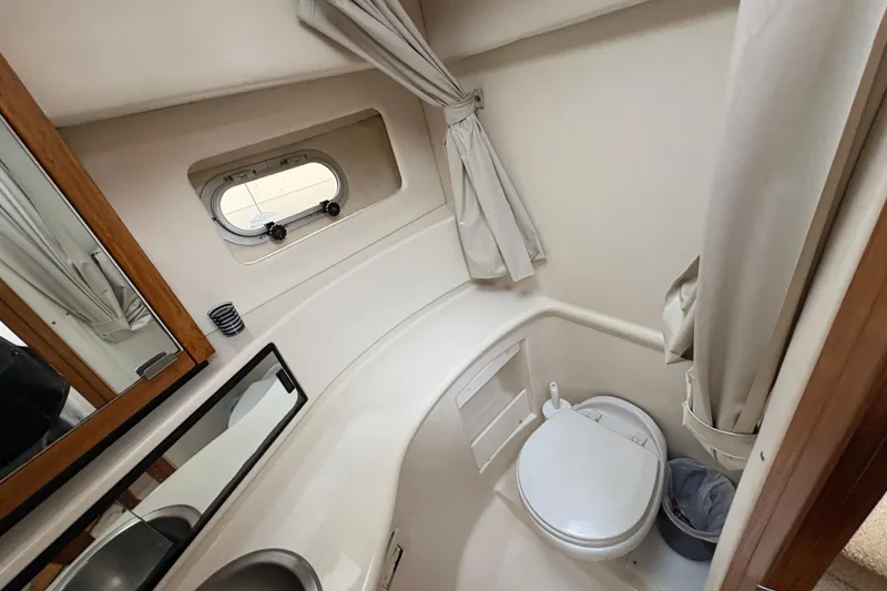 Slide: The Image of 1988 Bayliner 3587 Motoryacht bathroom with toilet, sink, mirror, and porthole window. - 76