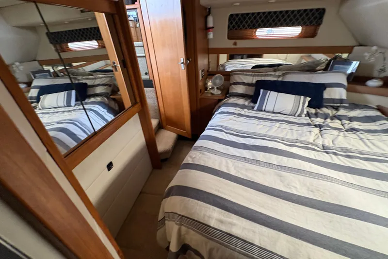 Slide: The Image of Cozy bedroom in 1988 Bayliner 3587 Motoryacht with striped bedding and wooden accents. - 90