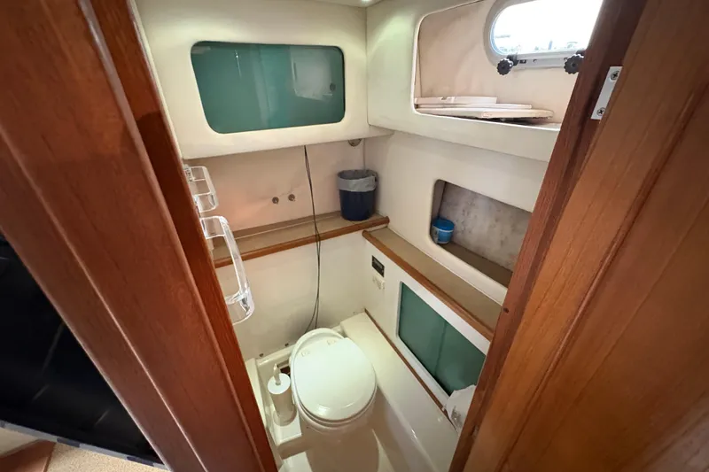 Slide: The Image of 1988 Bayliner 3587 Motoryacht bathroom with toilet, storage, and porthole window. - 92