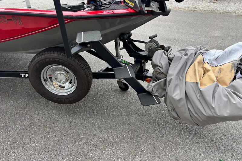 Slide: The Image of 2015 Tracker Pro Team 175 TXW boat on trailer with cover, parked on asphalt. - 2