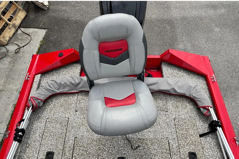 Slide: The Image of 2015 Tracker Pro Team 175 TXW boat seat, red and gray design, on textured deck. - 9