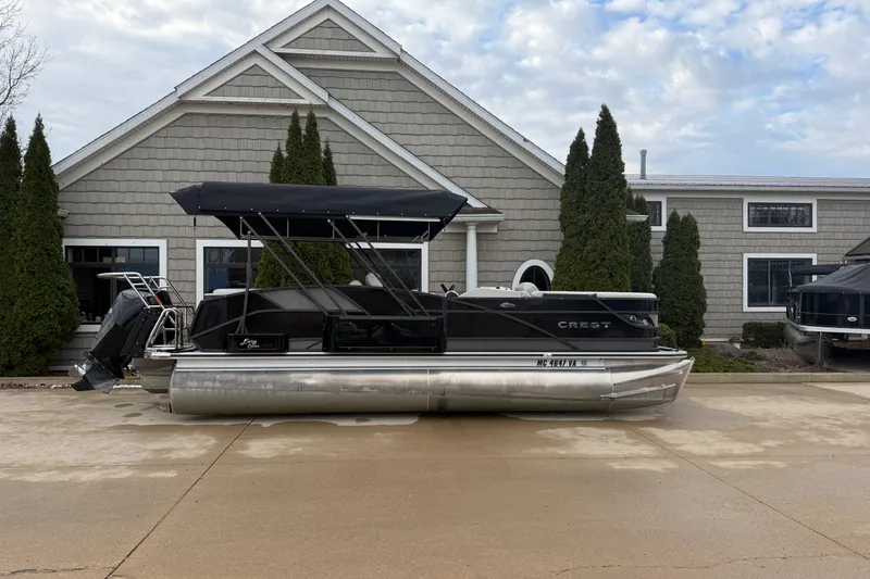 The Image of 2023 Crest Caribbean LX 230 pontoon boat parked outside a house with trees. - 0