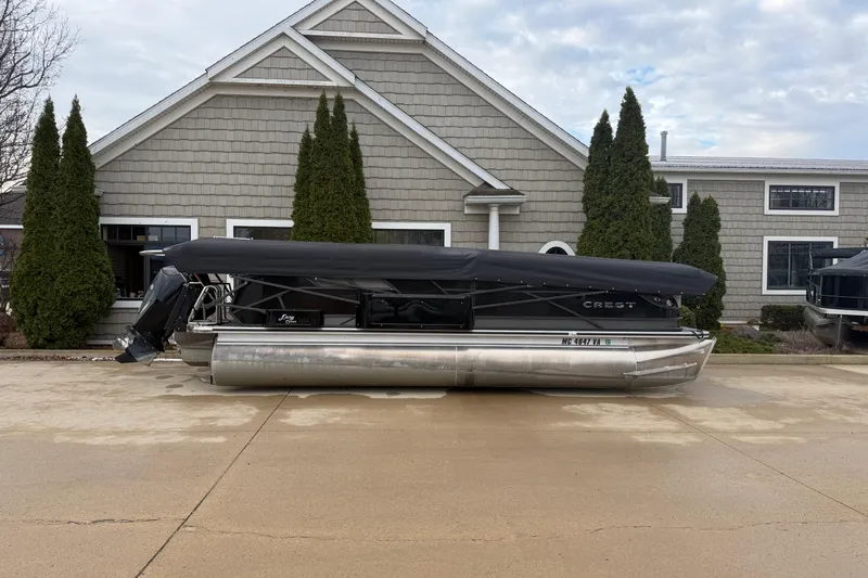 Slide: The Image of 2023 Crest Caribbean LX 230 pontoon boat parked in front of a house. - 2