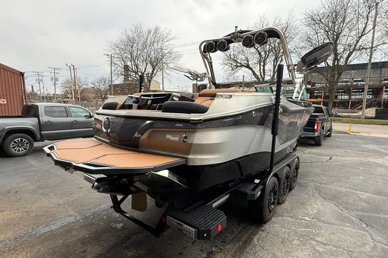 Slide: The Image of 2021 MasterCraft X26 boat on trailer, parked outdoors, showcasing sleek design and modern features. - 11