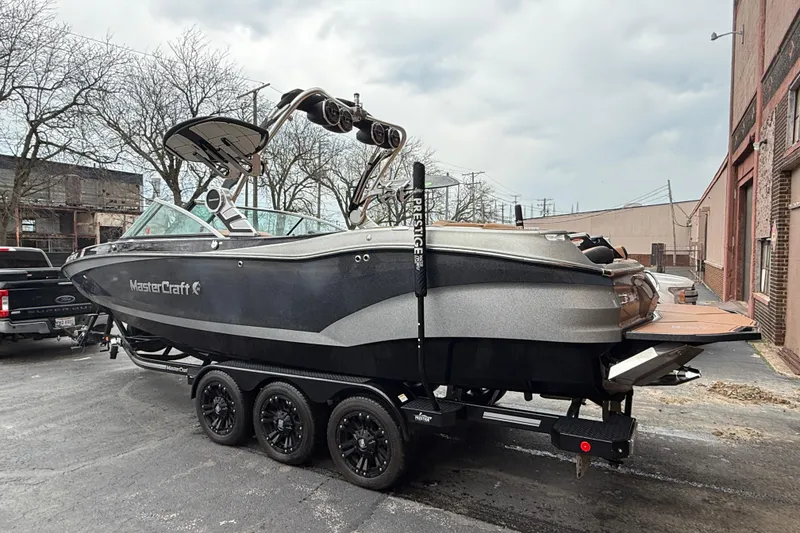 Slide: The Image of 2021 MasterCraft X26 boat on trailer, parked outdoors near industrial buildings. - 4