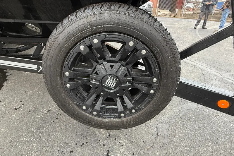 Slide: The Image of Black wheel of a 2021 MasterCraft X26 boat trailer on wet pavement. - 7