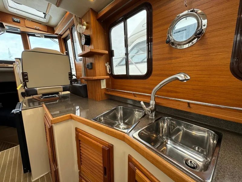 Slide: The Image of 2018 Ranger Tugs R-31S Ranger Tug interior kitchen with double sink and wooden cabinetry. - 25