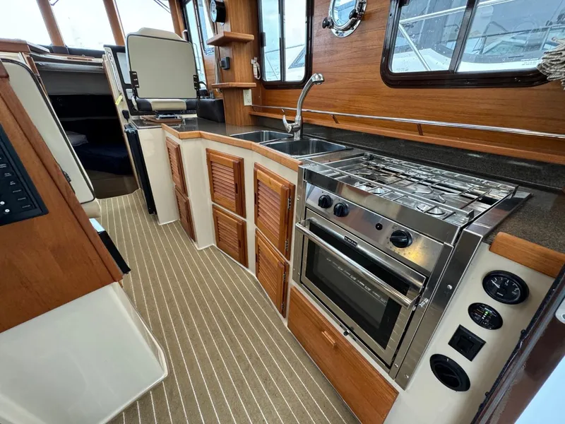 Slide: The Image of 2018 Ranger Tugs R-31S Ranger Tug kitchen with stove, sink, and wooden cabinets. - 29