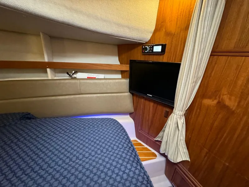 Slide: The Image of 2018 Ranger Tugs R-31S Ranger Tug cabin interior with bed, TV, and wooden paneling. - 50