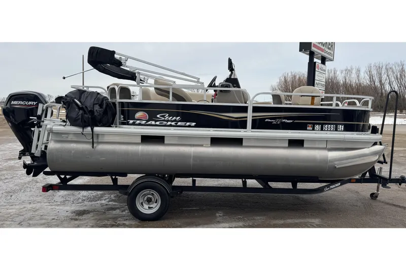 Slide: The Image of 2020 Sun Tracker Bass Buggy 18 DLX pontoon boat on trailer, parked outdoors. - 4