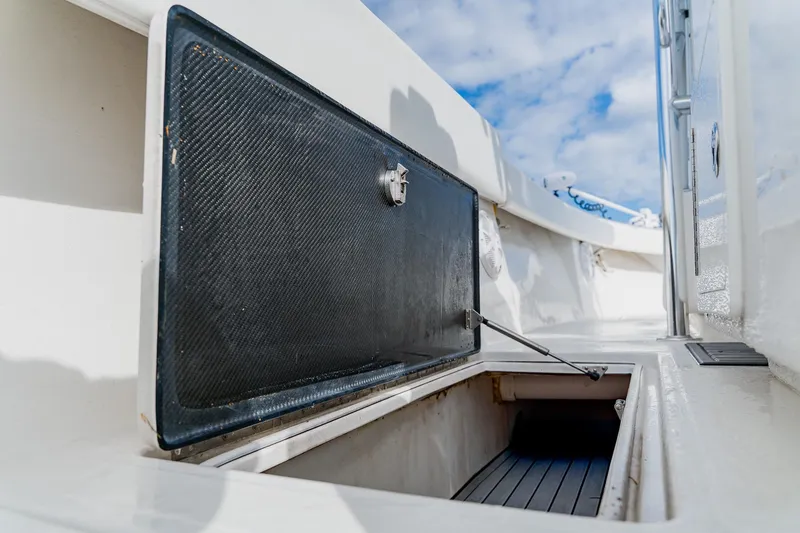 Slide: The Image of Open storage compartment on 2020 SeaHunter 31 Tournament boat deck under blue sky. - 43