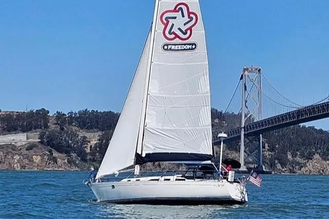 The Image of Sailboat Freedom 36 (1988) cruising near a bridge on a sunny day. - 0
