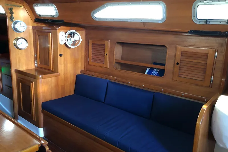 Slide: The Image of Interior of 1988 Freedom 36 sailboat with wooden cabinetry and blue cushioned seating. - 10