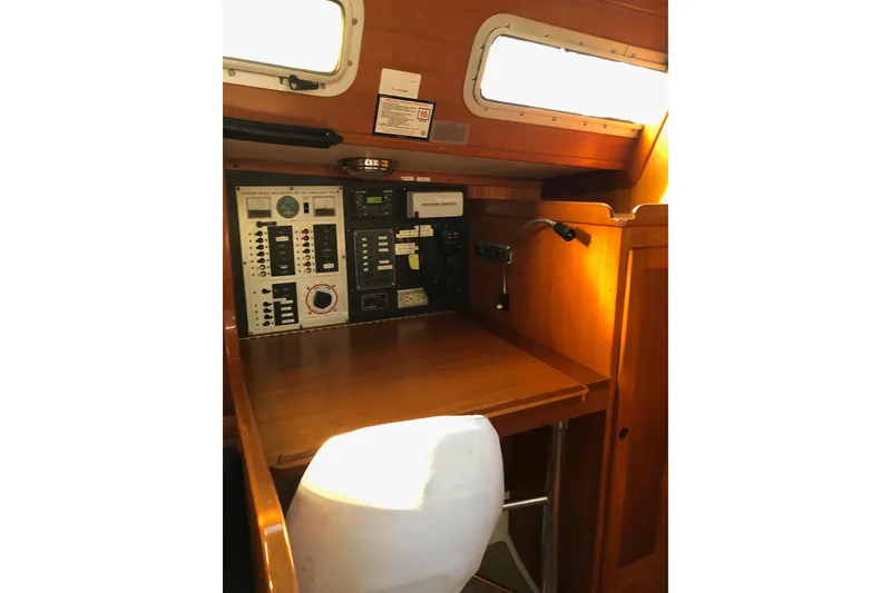 Slide: The Image of Navigation station inside 1988 Freedom 36 sailboat with control panels and wooden cabinetry. - 12