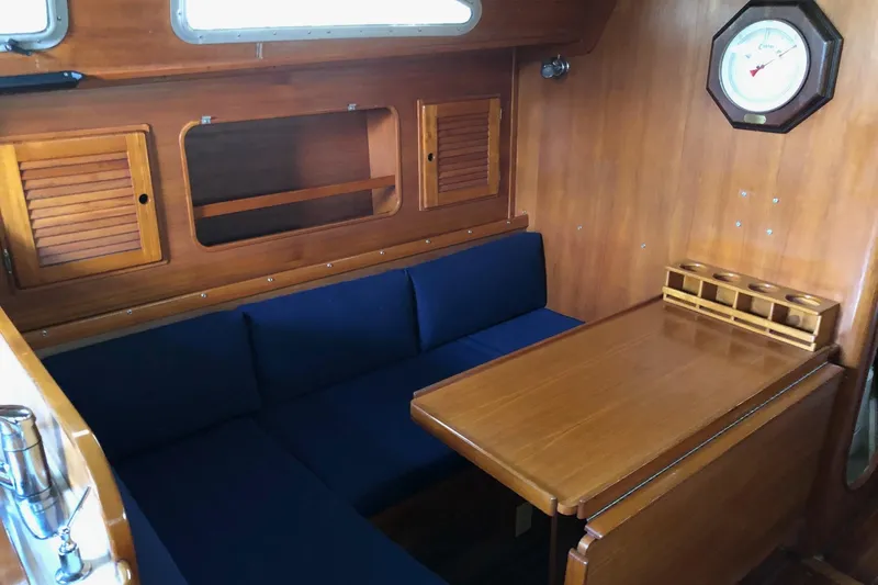 Slide: The Image of Interior of 1988 Freedom 36 sailboat with wooden table and blue cushioned seating. - 9