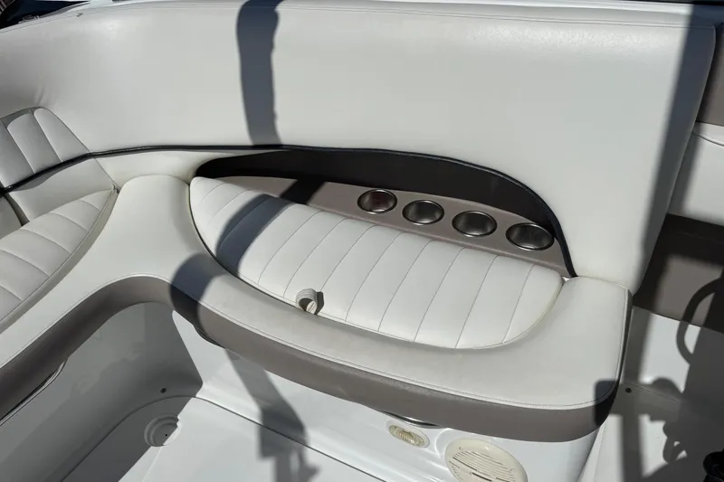 Slide: The Image of 2005 Cobalt 240 boat interior with white cushioned seating and cup holders. - 4