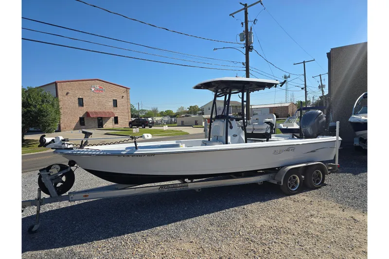 The Image of 2021 Blue Wave 2400 PureBay boat on trailer, parked outdoors under clear blue sky. - 0