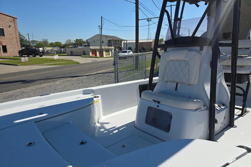 Slide: The Image of 2021 Blue Wave 2400 PureBay boat interior with seating and console, parked outdoors. - 12