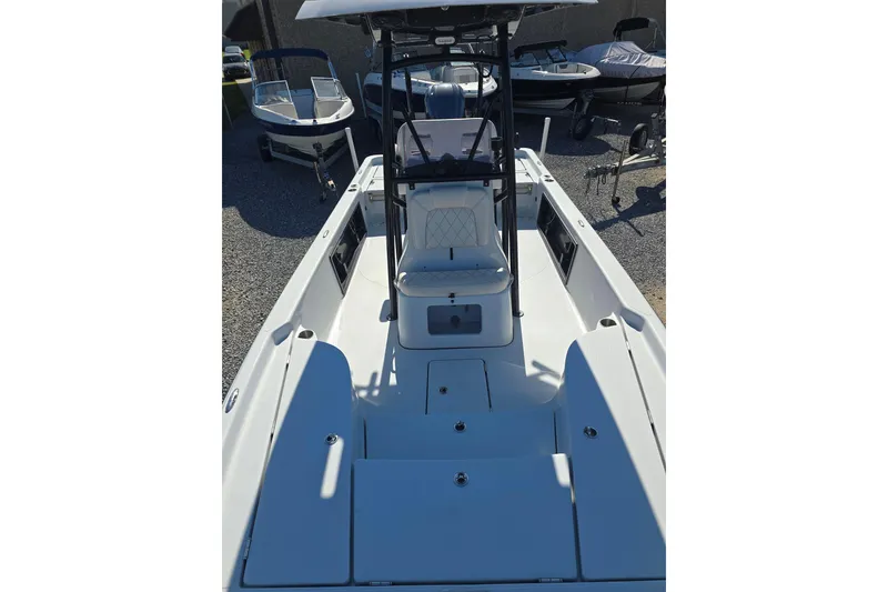 Slide: The Image of 2021 Blue Wave 2400 PureBay boat interior with seating and console, parked on gravel. - 18