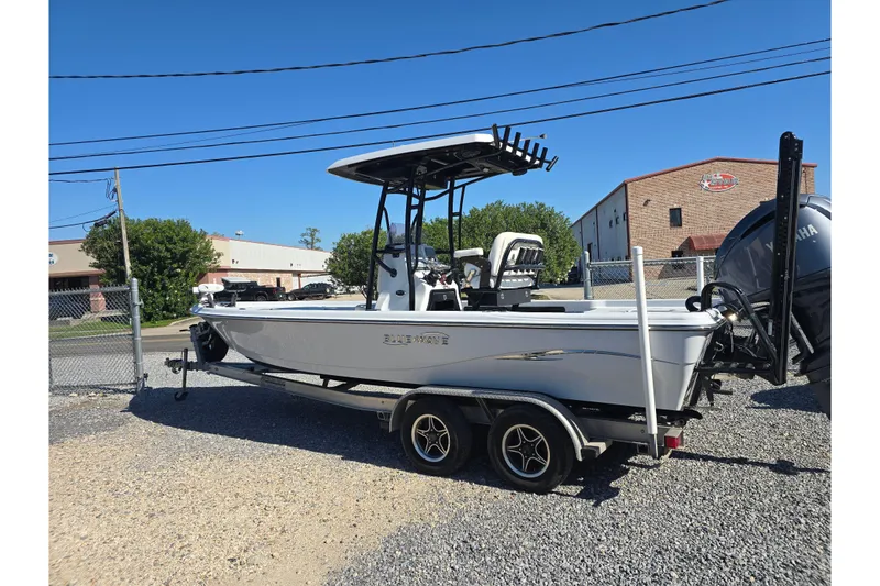 Slide: The Image of 2021 Blue Wave 2400 PureBay boat on trailer, parked outdoors under clear blue sky. - 2