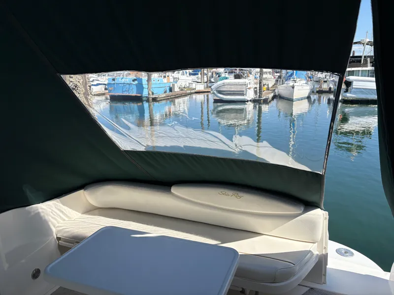 Slide: The Image of 1999 Sea Ray 340 Sundancer interior with marina view, featuring cushioned seating and table. - 12
