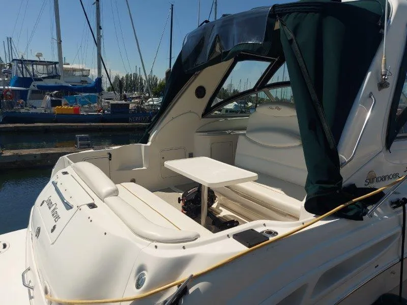 Slide: The Image of 1999 Sea Ray 340 Sundancer boat docked, featuring spacious seating and a small table. - 24