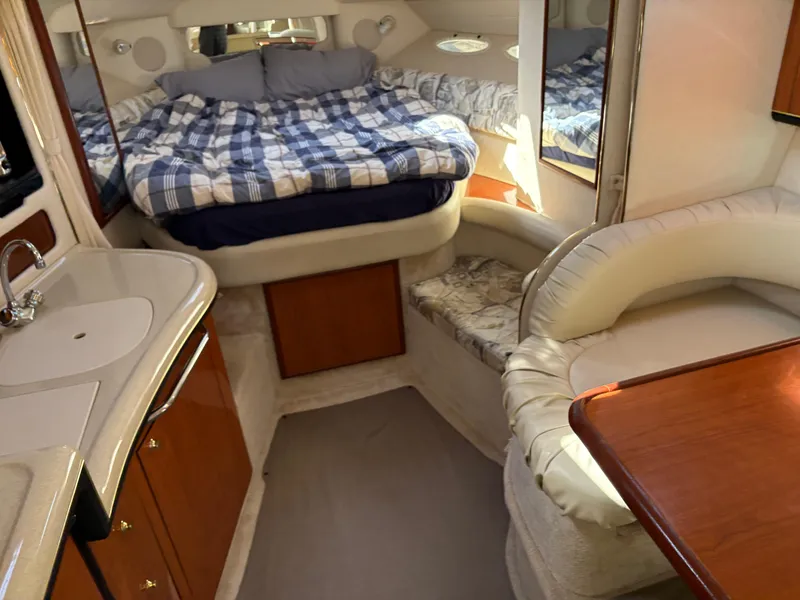 Slide: The Image of 1999 Sea Ray 340 Sundancer cabin interior with bed, seating, and kitchenette. - 25
