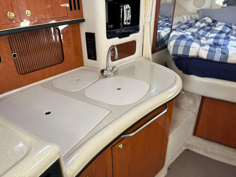 Slide: The Image of 1999 Sea Ray 340 Sundancer interior with kitchenette and cozy sleeping area. - 26