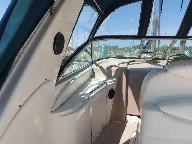 Slide: The Image of 1999 Sea Ray 340 Sundancer interior with white seating and windows, docked at marina. - 41