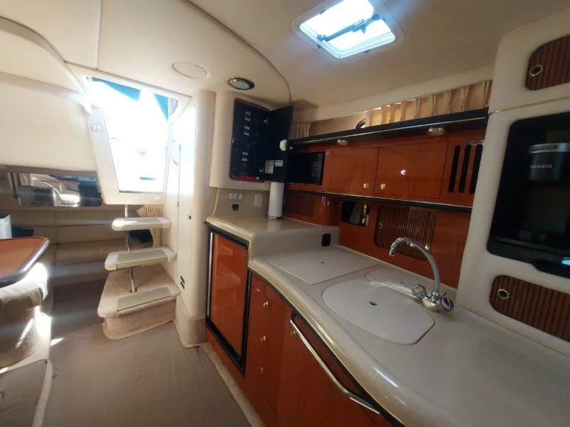 Slide: The Image of 1999 Sea Ray 340 Sundancer interior with kitchenette, seating, and stairs, showcasing luxury yacht design. - 46
