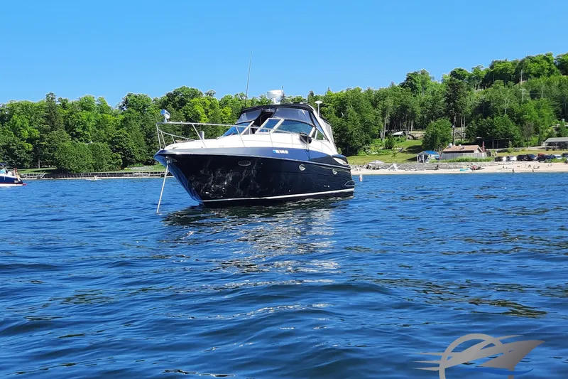 The Image of 2004 Cruisers Yachts 340 Express on serene lake with lush green shoreline. - 0