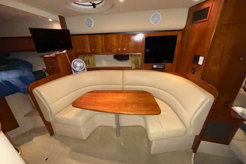 Slide: The Image of Interior of 2004 Cruisers Yachts 340 Express with beige seating and wooden table. - 13