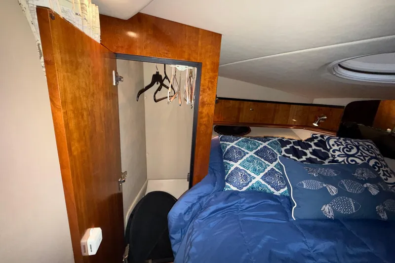 Slide: The Image of Interior of 2004 Cruisers Yachts 340 Express with bed, pillows, and open wooden closet. - 16