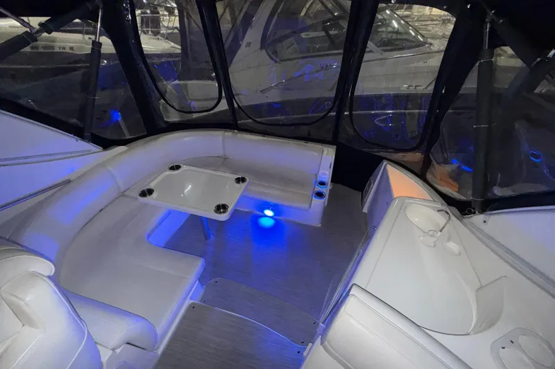 Slide: The Image of 2004 Cruisers Yachts 340 Express interior with seating and table, illuminated by blue lighting. - 23