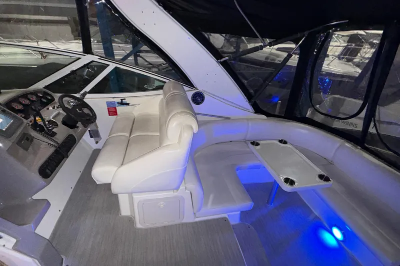 Slide: The Image of 2004 Cruisers Yachts 340 Express cockpit with white seating and illuminated blue lighting. - 31
