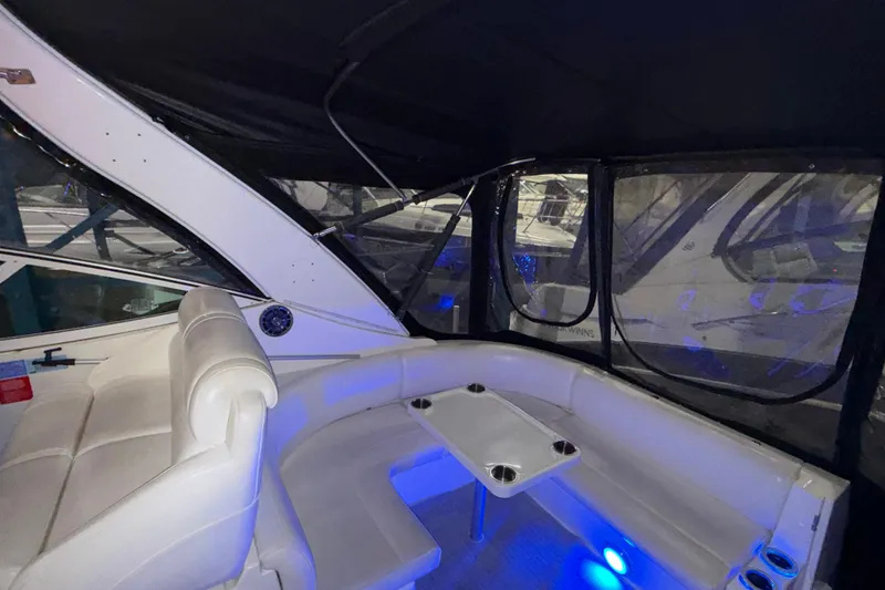 Slide: The Image of 2004 Cruisers Yachts 340 Express interior with white seating and table, under blue lighting. - 33