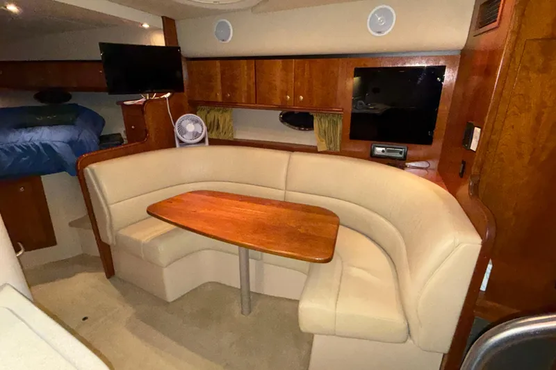 Slide: The Image of 2004 Cruisers Yachts 340 Express interior with beige seating and wooden table. - 4