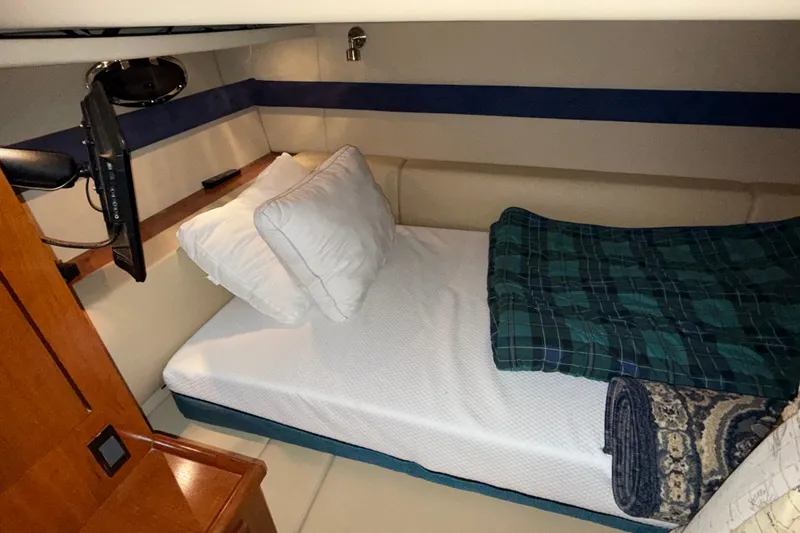 Slide: The Image of 2004 Cruisers Yachts 340 Express cabin with bed, pillows, and TV. - 8