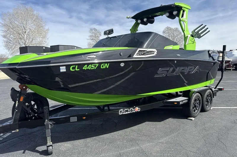 The Image of 2022 Supra SA 450 boat in black and green on a trailer, parked outdoors. - 1