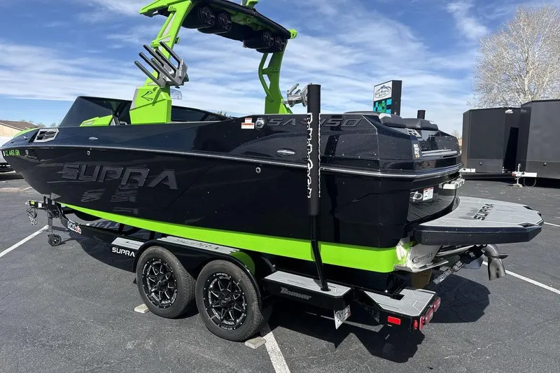 Slide: The Image of 2022 Supra SA 450 boat in black and green on a trailer, parked outdoors. - 3